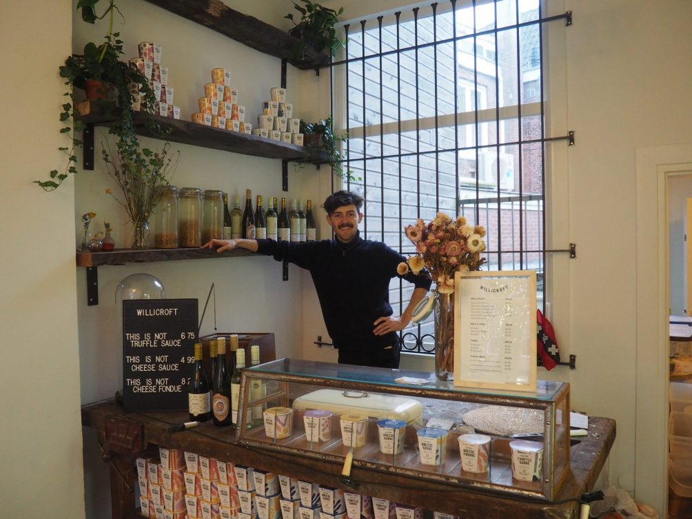 Der Gründer von Willicroft steht hinter einer Ladentheke. Dort wird veganer Käse verkauft