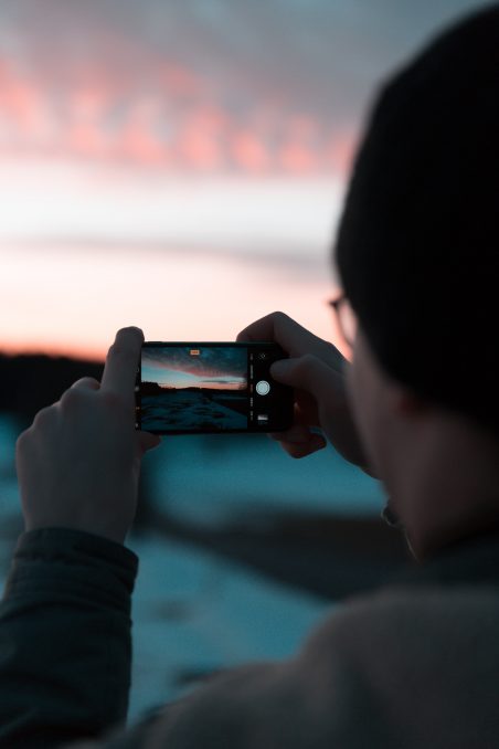 Man takeing photo with mobile phone with sunset