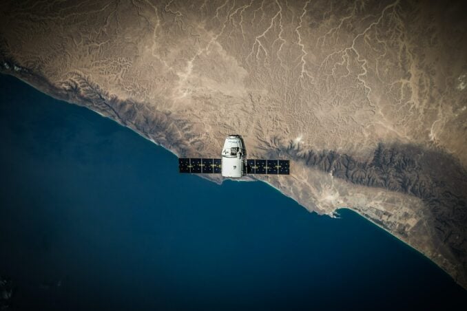 A satellite is seen from above hovering over Earth